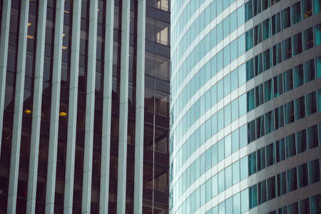 Business abstract - modern office building covered with glass against blue sky. Details of...