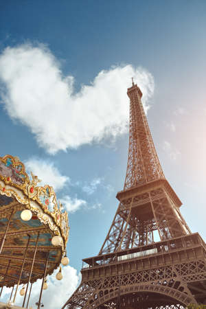 Love in Paris. Eiffel tower and carousel against heart shape in clouds - Valentine s Day concept, or couples romantic trip in love idea. Eiffel Tower is one of the most iconic landmarks of France, and Paris is city of love.の写真素材