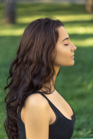 Close-up profile portrait of fitness girl. Young girl doing yoga in the park.の写真素材