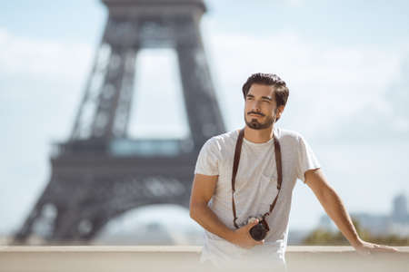 Paris Eiffel Tower tourist with camera taking pictures in front of the Eiffel tower, Paris, France. Young professional photographer handsome man in casual clothes outdoors in Europe.の写真素材