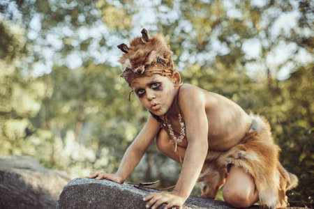 Funny caveman, manly boy. Prehistoric tribal man outdoors on nature. Primitive ice age man in animal skin. Reconstruction of Neanderthal and cro-magnon lifeの写真素材