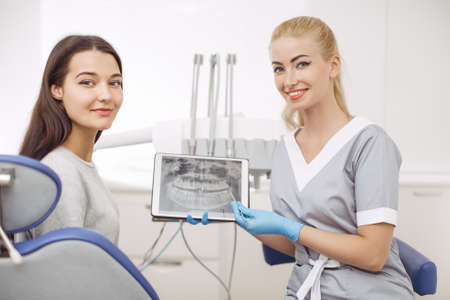 Dentist and patient choosing treatment in a consultation with medical equipment in the background....
