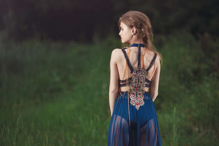 Elf. Beautiful girl in magic forest. Fantasy young woman in woods outdoors. Creative portrait of young model in fantastic costume. Back view.の写真素材