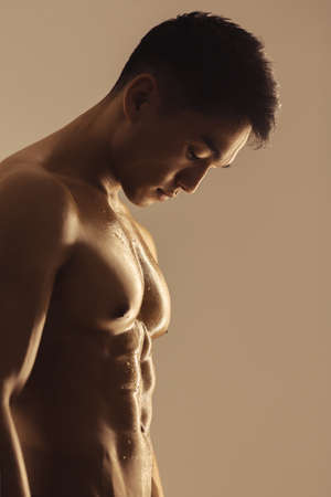 Portrait of athletic muscular Asian man standing on a grey background. Attractive confident young...