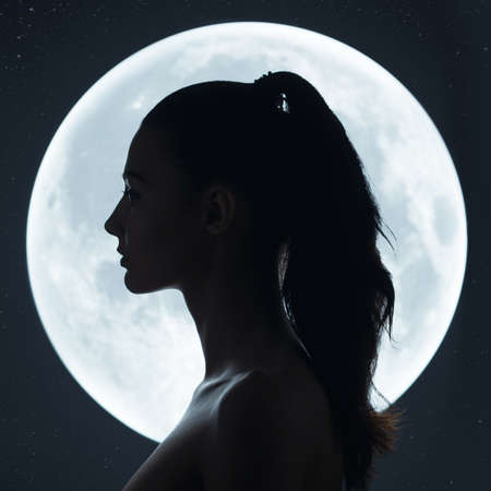 Fine art fashion studio portrait of a sensual woman against the night sky and a full moon....