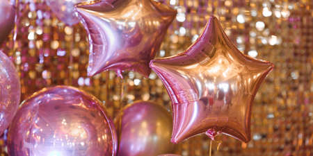 Golden balloons against holiday glowing bokeh backgroundの写真素材