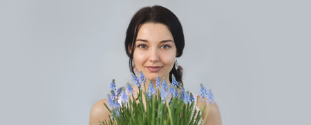 Beautiful young woman holding spring flowers bouquet in hands. Sensual romantic mixed race female florist with mouse Hyacinth Muscari. Life lover, zero waste, spring mood concept.の写真素材