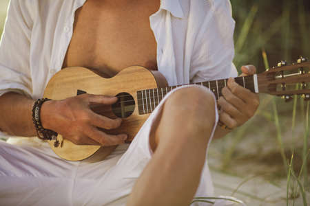 Close-up Man Playing Ukulele During Summer Beach Vacationの写真素材