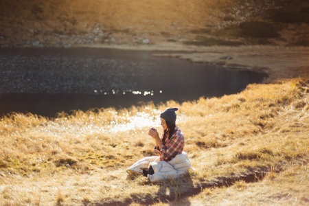 Traveler Woman Hiking in the Mountains With Cup of Coffee Near the Lakeの写真素材