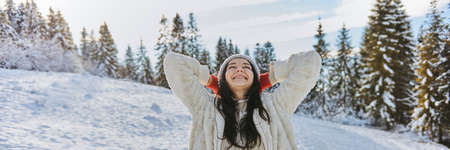 Woman in Winter Clothes Raised Hands Outdoors in Forestの写真素材