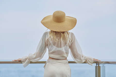 Back view of the Woman in Elegant Beach Outfit Outdoors Against Sea Background During Summer Vacationsの写真素材
