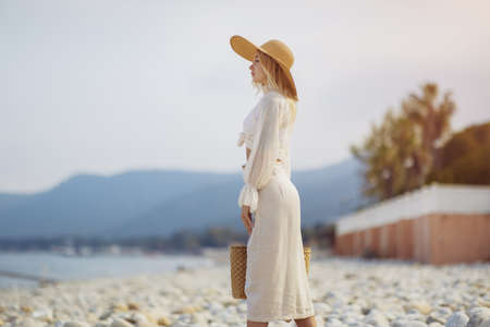 Woman in Elegant Beach Outfit Outdoors Against Palm Trees on the Background During Summer Vacationsの写真素材