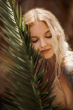 Sexy Beach Blonde Girl in Knitted Bikini With Palm Leaf Outdoors on Natureの写真素材