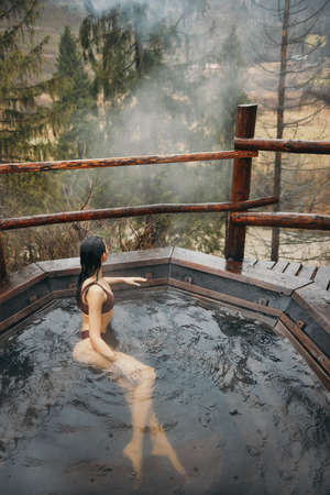 Woman in bikini bathing in Japanese style bath outdoorsの写真素材