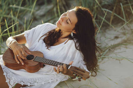 Woman With Ukulele During Summer Beach Vacation Near the Sea