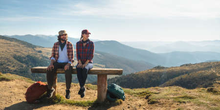 Couple of Hikers With Backpacks in Front of Landscape Valley View on Top of a Mountainの写真素材