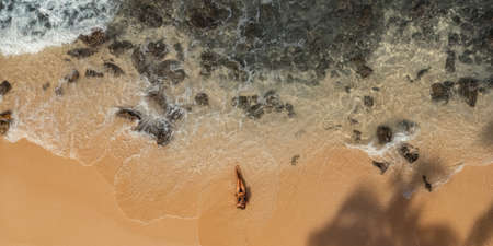 Top Aerial View of Tanned Woman in Bikini on the Rocky Beach on Summer Weekend Vacation