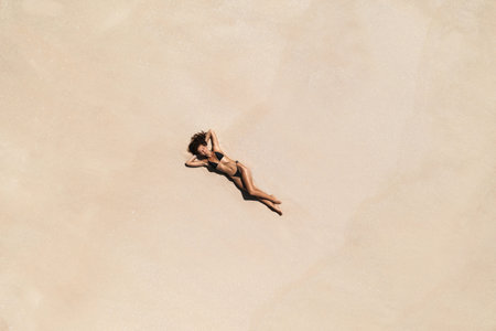 Top Aerial Drone View of Woman in Swimsuit Bikini Relaxing and Sunbathing on Beach White Sand