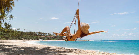 Bikini Beach Girl Model in Black Swimsuit on Palm Tree Swing on Tropical Sea Shore During Summer Vacationsの写真素材