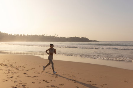 Silhouette of the woman running alone at beautiful sunset on the beach. Summer sport and freedom concept. Athlete training outdoors. High quality photoの写真素材