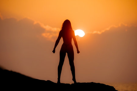 Silhouette of a Mentally and Physically Strong Woman on a Top at Sunriseの写真素材