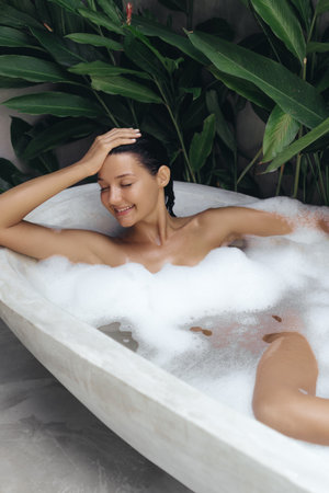 Happy Woman Relaxing in Bubble Bath Surrounded by Tropical Greenery