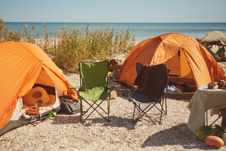 Empty Camping Chairs by Tents on Beach