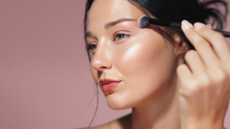 Model Applying Shimmering Highlighter on Cheekbone with Makeup Brushの写真素材