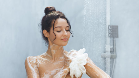Woman with Hair Bun Enjoying a Relaxing Shower with Foamy Loofah