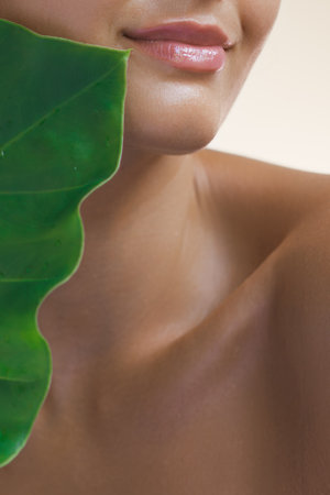 Womans Glossy Lips and Green Leaf Close-upの写真素材