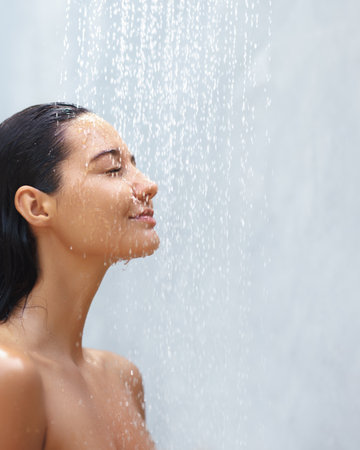 Relaxed Woman with Wet Hair Enjoying a Soothing Shower, Eyes Closed in Peaceの写真素材