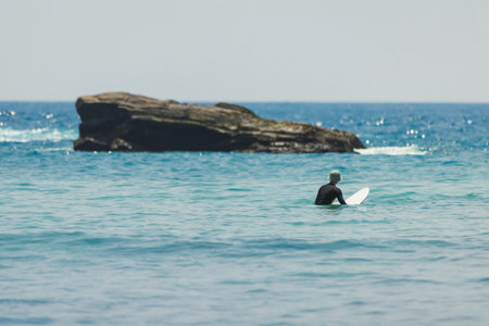 Surfer Waiting for Waves in Calm Waters at Hiriketiya Beach, Sri Lankaの写真素材
