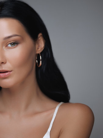 Close-Up of Elegant Woman with Flawless Skin and Gold Hoop Earringsの写真素材