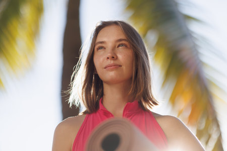 Freckled Woman Holding Yoga Mat Under Palm Trees, Ready for Outdoor Yoga Session