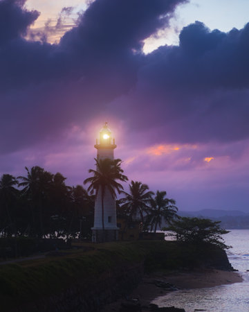 Galle Fort Lighthouse Illuminated at Sunset with Dramatic Clouds and Palmsの写真素材