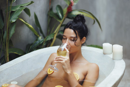 Woman Relaxing in Tropical Bath with Wine Surrounded by Candlesの写真素材