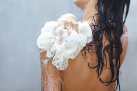 Womans Back Lathered with Foamy Loofah in Refreshing Shower