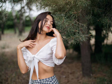 Sensual Woman in White Blouse and Checkered Skirt Posing Outdoorsの写真素材