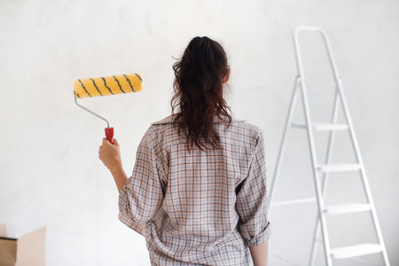 Woman Holding Paint Roller from Behind During Home Renovation Projectの写真素材