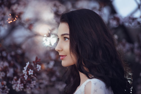 Elegant Woman Admiring Cherry Blossoms At Twilight