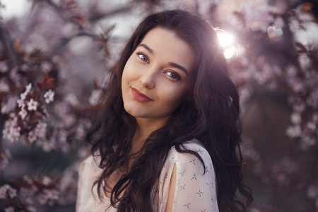 Smiling Woman Among Cherry Blossoms In Soft Spring Lightの写真素材