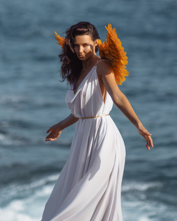Elegant Woman With Golden Wings In White Dress Walking By The Seaの写真素材