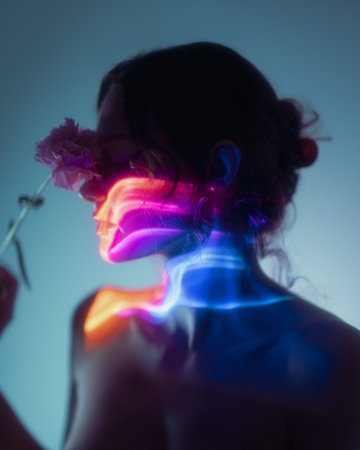 Artistic Female Silhouette With Neon Light Effects Holding a Pink Flowerの写真素材