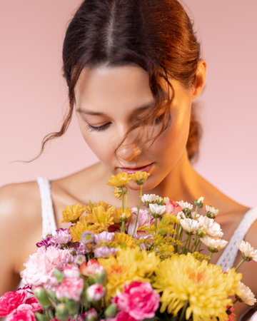 Woman With Eyes Closed Smelling Colorful Spring Bouquet in Warm Lightの写真素材