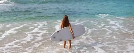 Woman with Surfboard in the Ocean Preparing to Surf on a Tropical Beach