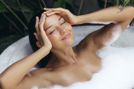 Smiling Woman Enjoying Bubble Bath With Eyes Closed In Tropical Spa Setting