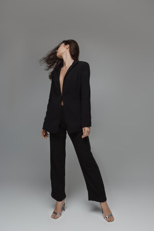 Stylish Woman In Black Suit Striking A Confident Poseの写真素材