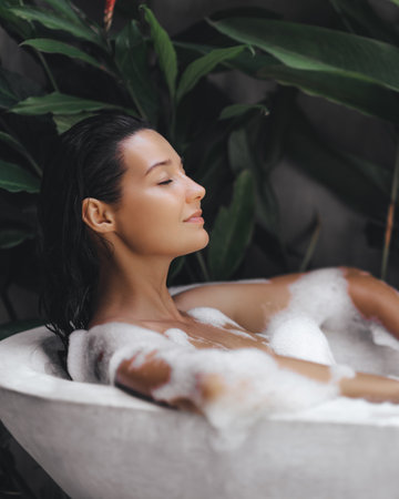 Peaceful Woman Relaxing in Outdoor Bubble Bath Surrounded by Lush Greeneryの写真素材