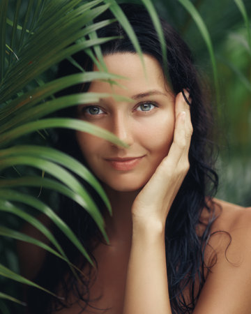 Beautiful Woman Posing Behind Tropical Leaves With Natural Glowの写真素材
