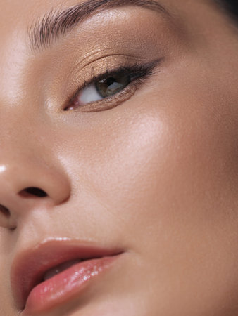 Close-Up of Woman s Face with Golden Eyeshadow and Glossy Lipsの写真素材